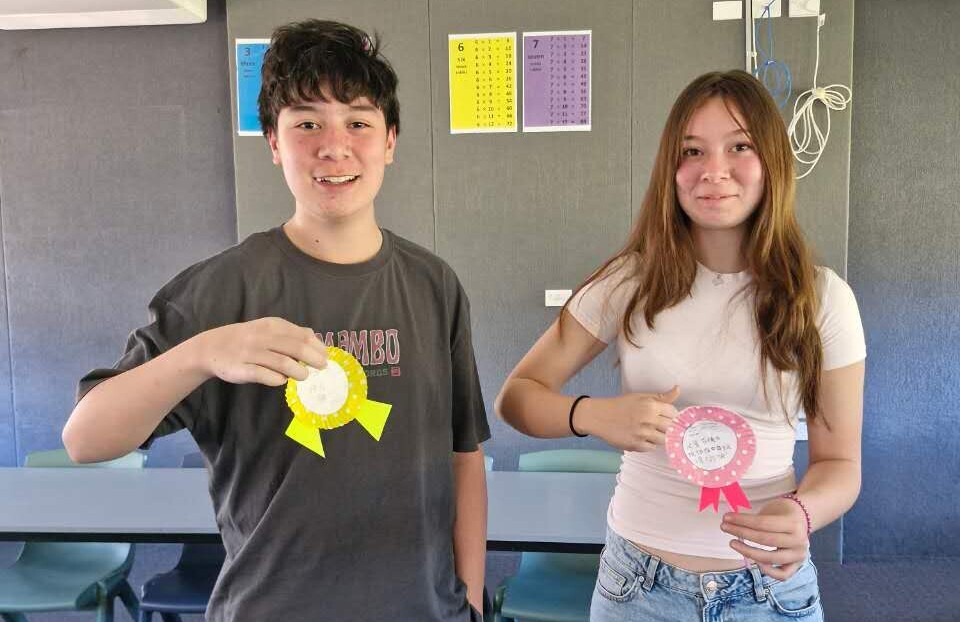 Students hold up their Father's Day medal craft